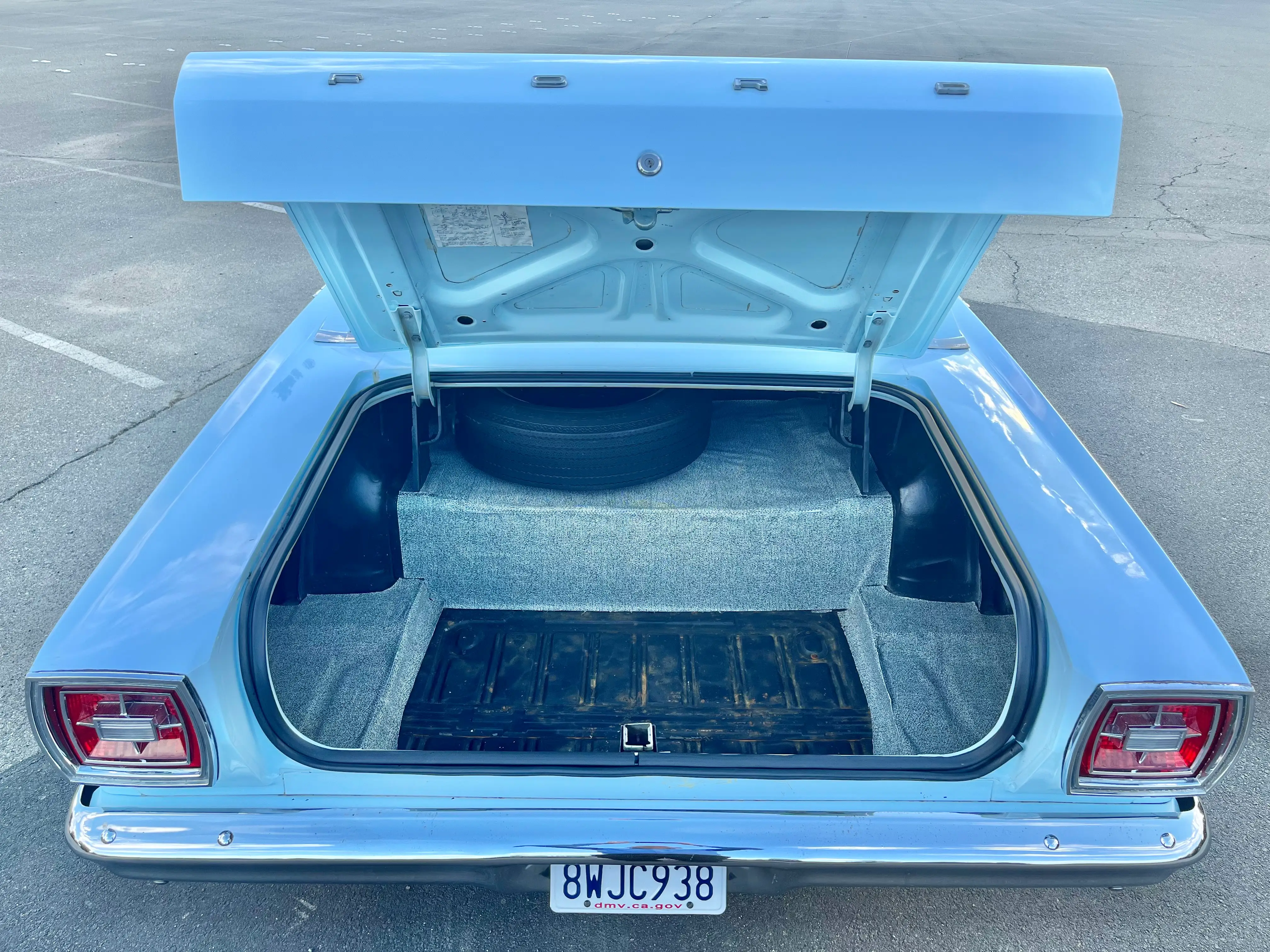 Open trunk of a 1966 Ford Custom four-door sedan showing the spare tire and trunk floor