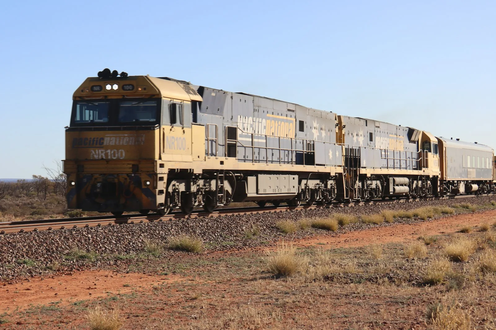 Diesel-electric freight locomotive sounding its train horn at a grade crossing — the source sound that aftermarket train horns replicate