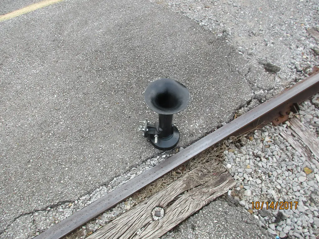 Nathan Airchime locomotive horn resting beside a railroad track — the real train-horn sound that budget 3-trumpet kits like the Vevor try to imitate
