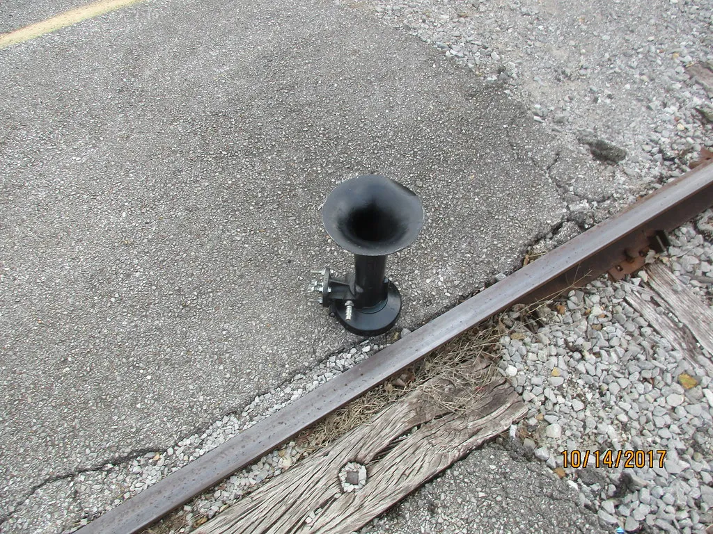 Nathan Airchime locomotive horn resting beside a railroad track — the real train-horn sound that budget 3-trumpet kits like the Vevor try to imitate