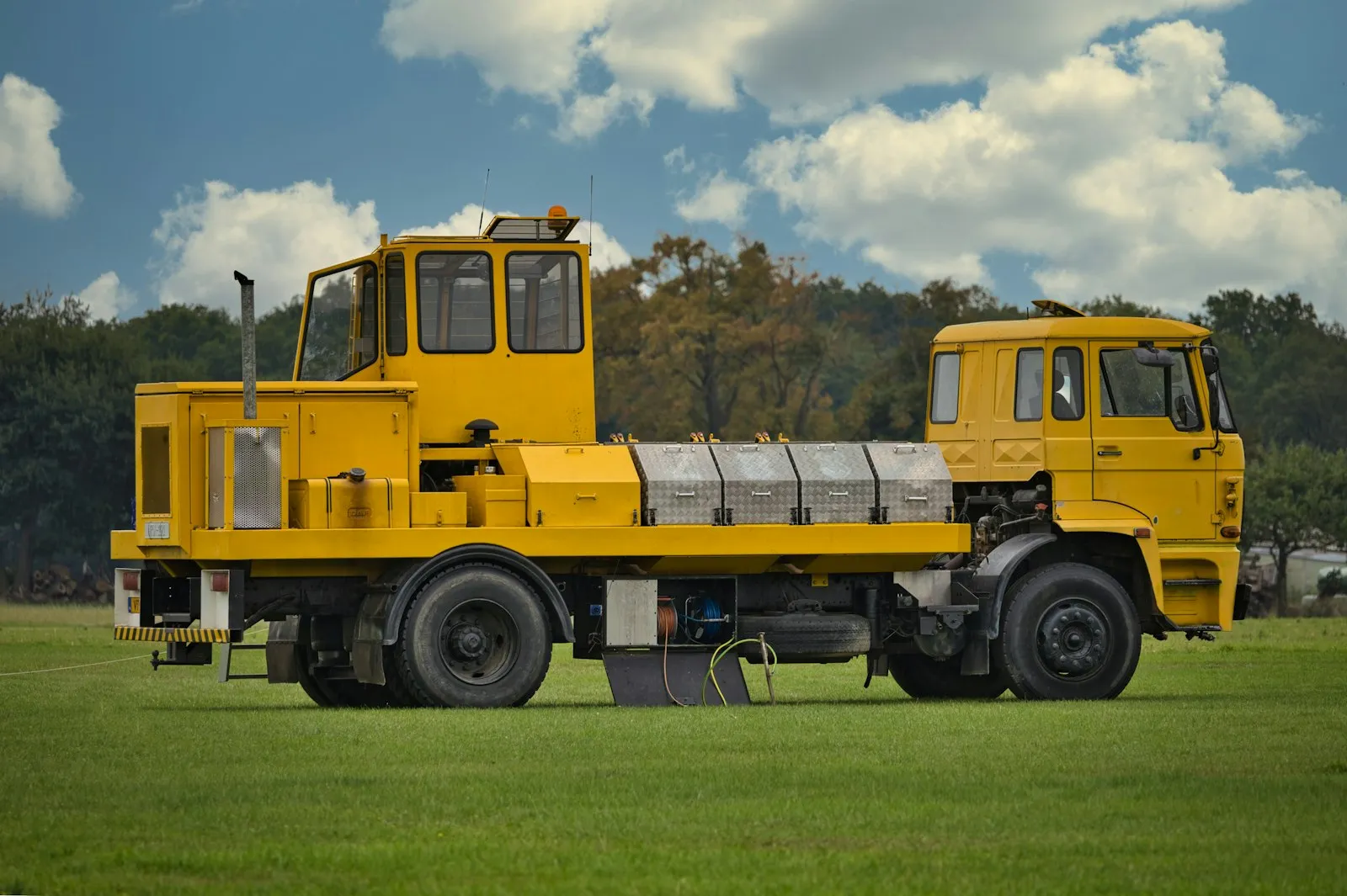 A yellow specialized truck on a grassy field