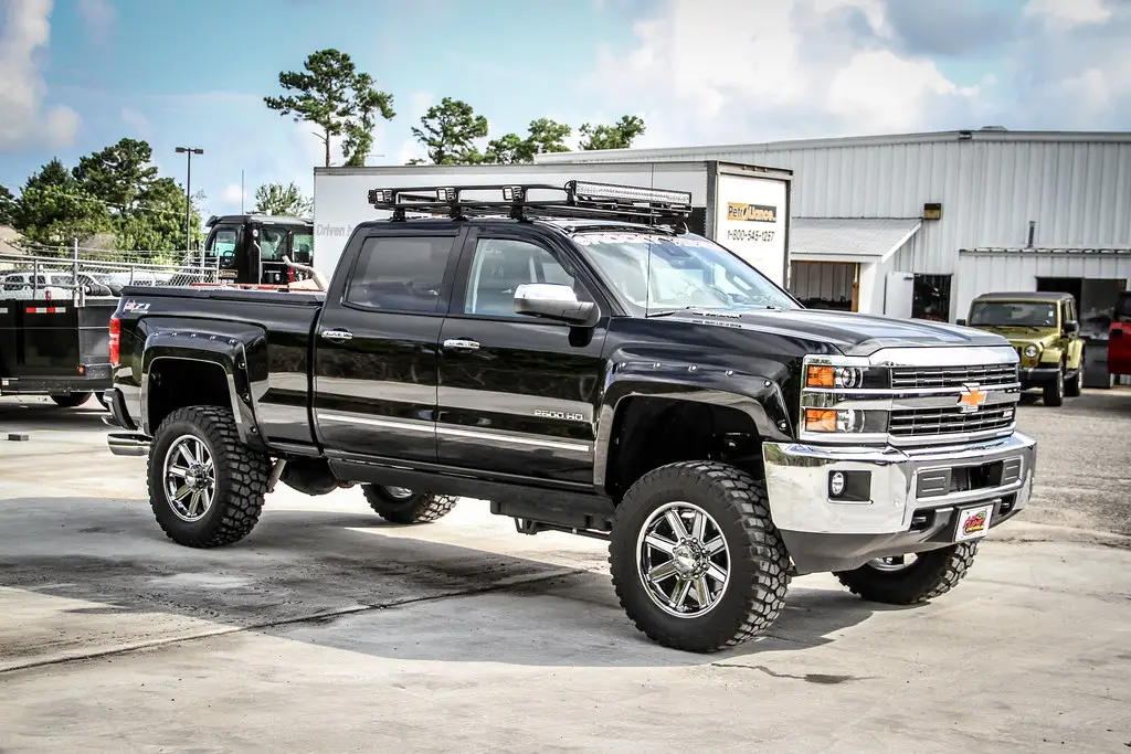 Lifted black Chevy Silverado 2500HD on oversize tires — the type of full-size truck the Kleinn USTL-230 spare tire location kit is built for