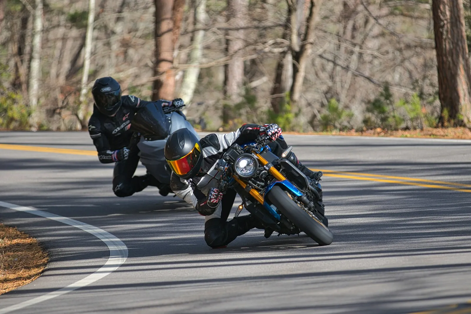 Two motorcyclists leaning into a sharp turn on a road
