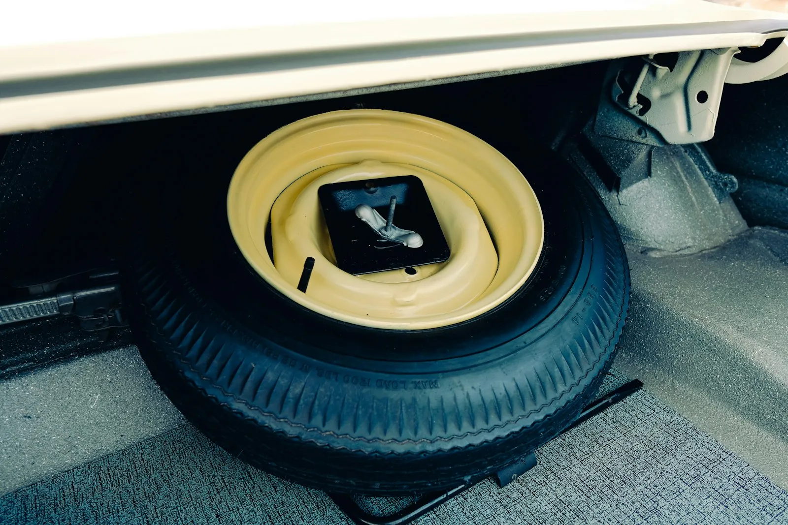 Spare tire and jack in a car trunk — the location swapped out for the train horn assembly in a spare-tire-mount install