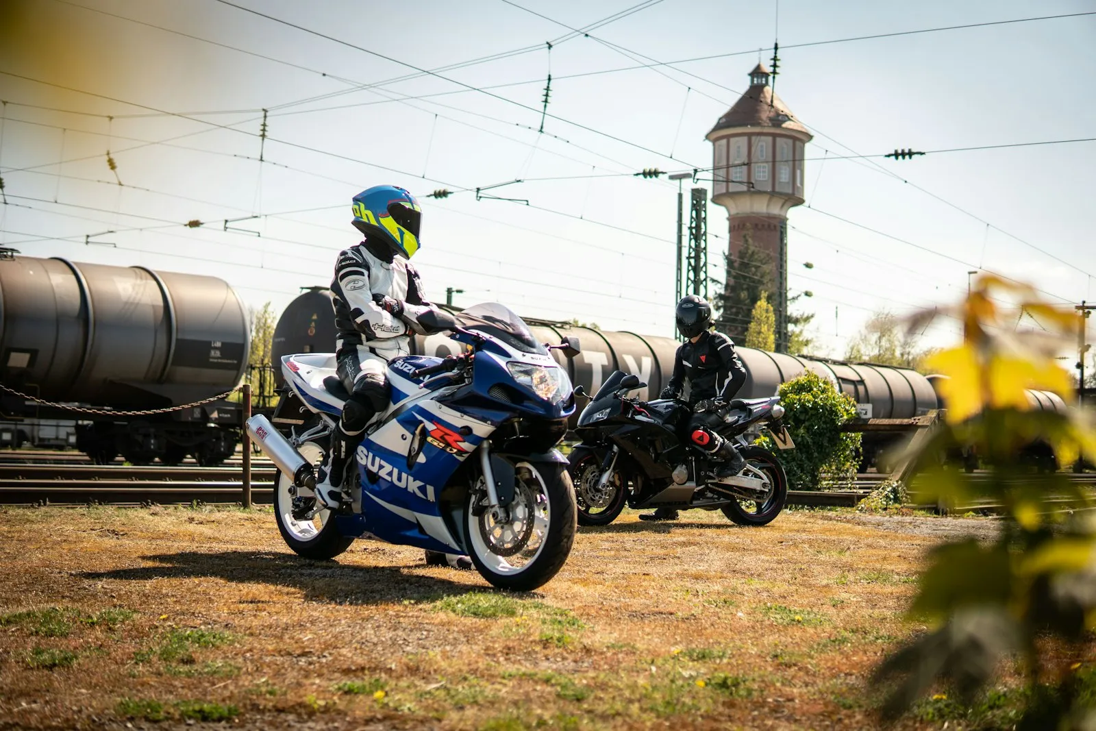 Two bikers are posing near train tracks